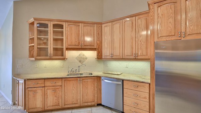 kitchen with decorative backsplash, appliances with stainless steel finishes, light stone countertops, sink, and light tile patterned floors