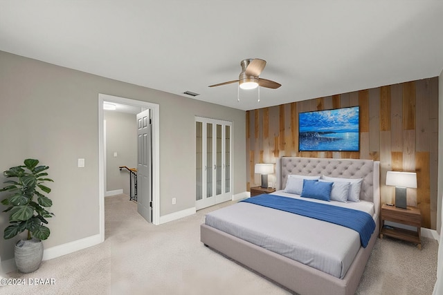 bedroom featuring wood walls, ceiling fan, and light carpet