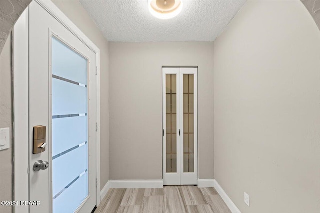 entryway with light hardwood / wood-style floors and a textured ceiling