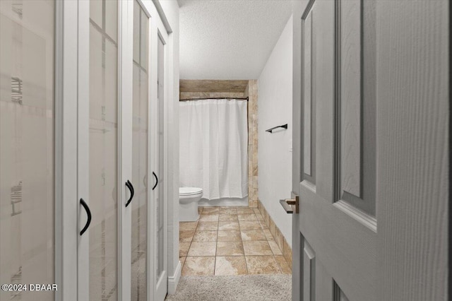 bathroom featuring toilet, a textured ceiling, and curtained shower