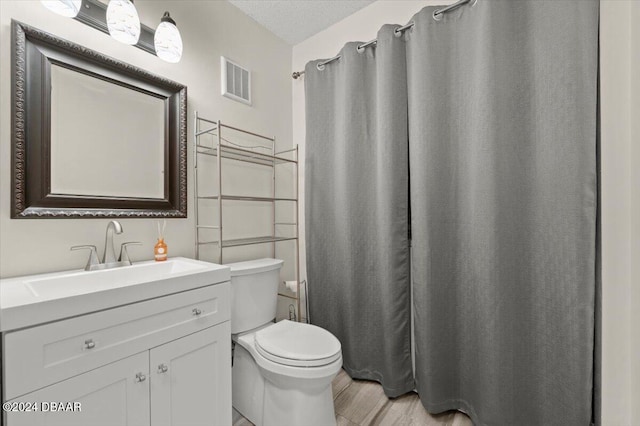 bathroom with toilet, a shower with curtain, vanity, and a textured ceiling