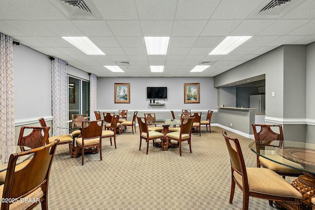 carpeted dining space featuring a drop ceiling