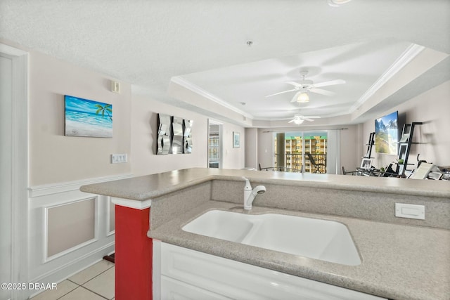 kitchen with a raised ceiling, crown molding, sink, and light tile patterned floors