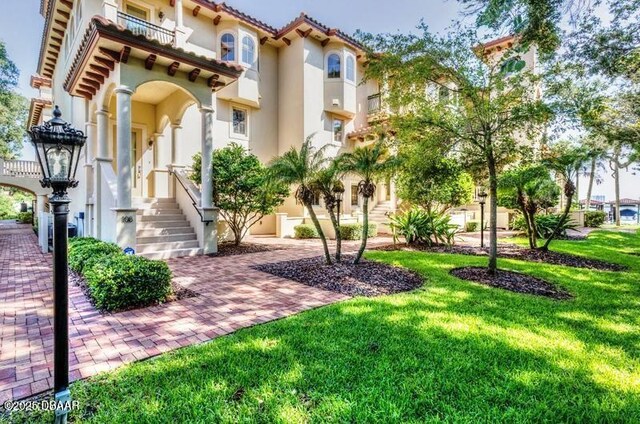 5090 Riverside Dr Unit 108, Port Orange, FL 32127 - view of front facade with stucco siding, a front yard, and a balcony