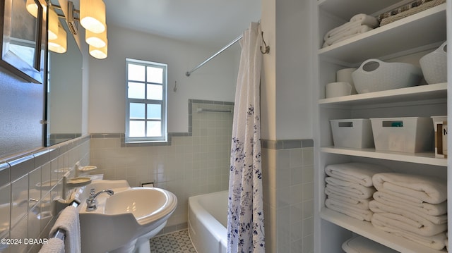 bathroom with shower / bath combo, tile walls, and sink