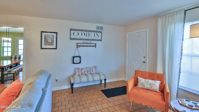 living area featuring a wealth of natural light, tile patterned flooring, and a chandelier