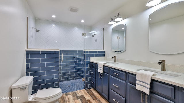 bathroom with vanity, toilet, wood-type flooring, and tile walls