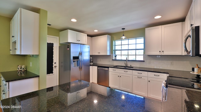 kitchen with appliances with stainless steel finishes, sink, decorative light fixtures, dark stone countertops, and white cabinets