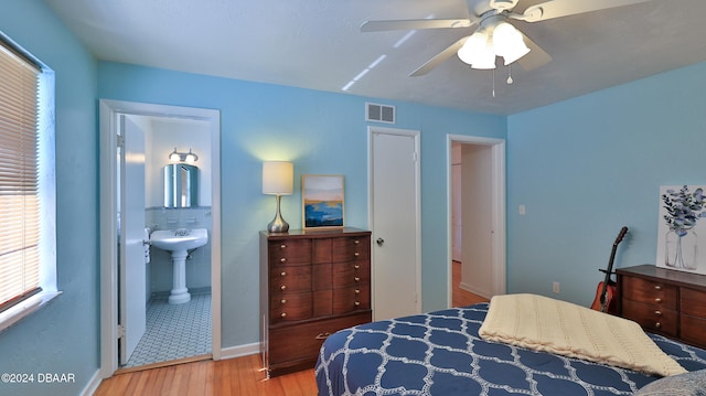 bedroom with light hardwood / wood-style flooring, ensuite bath, ceiling fan, and sink