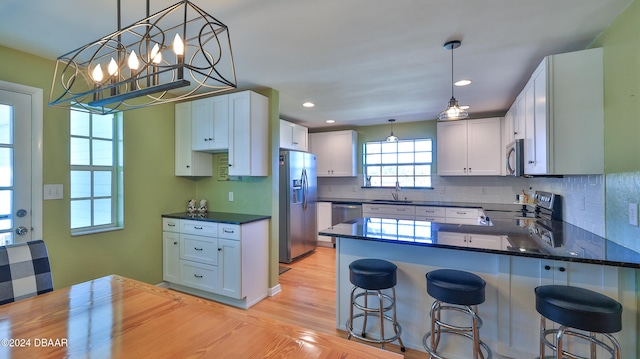 kitchen featuring white cabinets, appliances with stainless steel finishes, a breakfast bar, and light wood-type flooring