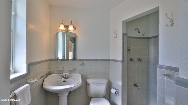 bathroom featuring toilet, tile walls, and tiled shower