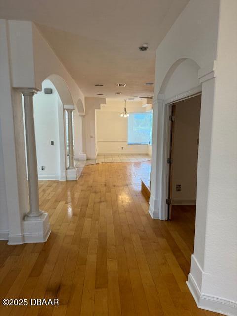 594 Marisol Dr, New Smyrna Beach, FL 32168 - hallway featuring ornate columns, light wood-style flooring, arched walkways, and baseboards