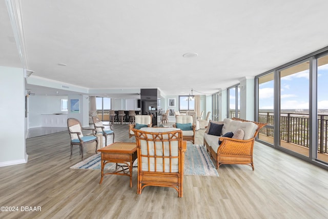 living room with light wood finished floors, a notable chandelier, floor to ceiling windows, and baseboards