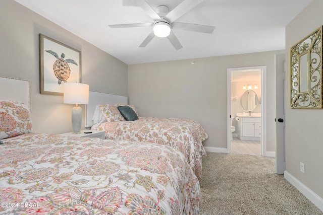 carpeted bedroom featuring baseboards, ensuite bathroom, and ceiling fan