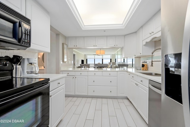 kitchen with black appliances, a sink, light countertops, decorative backsplash, and a raised ceiling