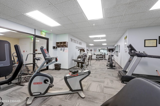 gym with a paneled ceiling, baseboards, and carpet floors