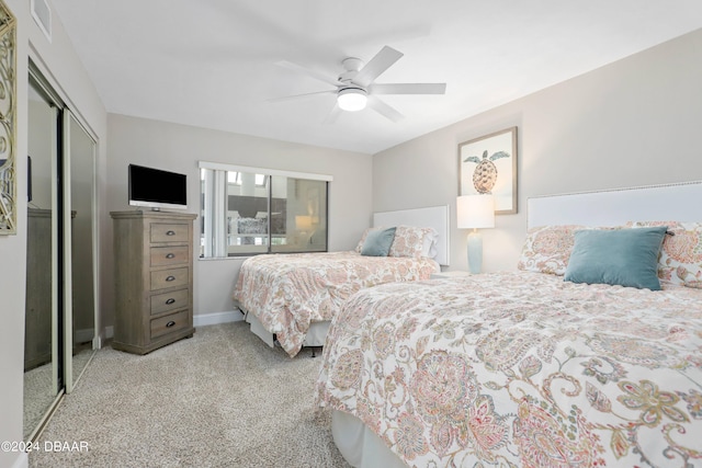 carpeted bedroom featuring a closet, visible vents, baseboards, and a ceiling fan