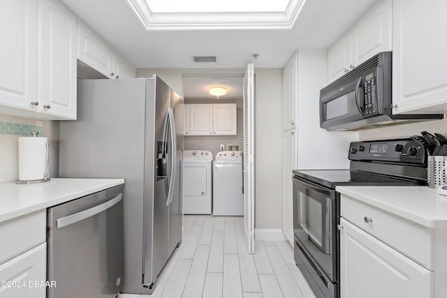 kitchen with visible vents, black appliances, washer and clothes dryer, backsplash, and white cabinetry