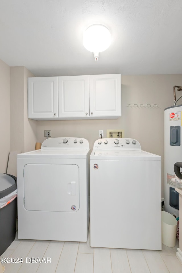 clothes washing area featuring water heater, cabinet space, and independent washer and dryer