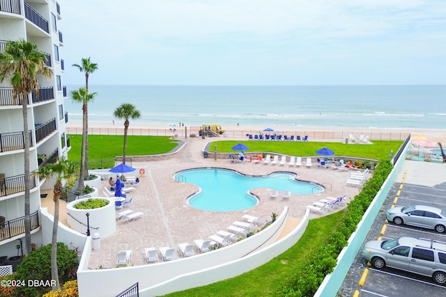 community pool with a view of the beach, a patio, and a water view