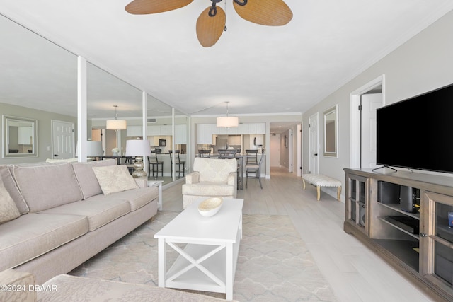 living area with lofted ceiling, crown molding, light wood finished floors, and ceiling fan