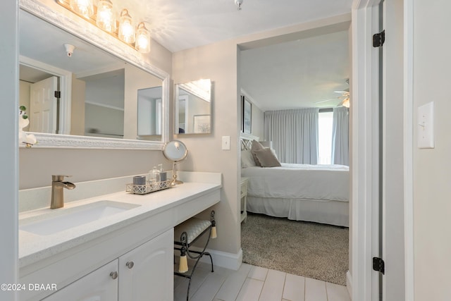 ensuite bathroom featuring vanity, ceiling fan, baseboards, and connected bathroom