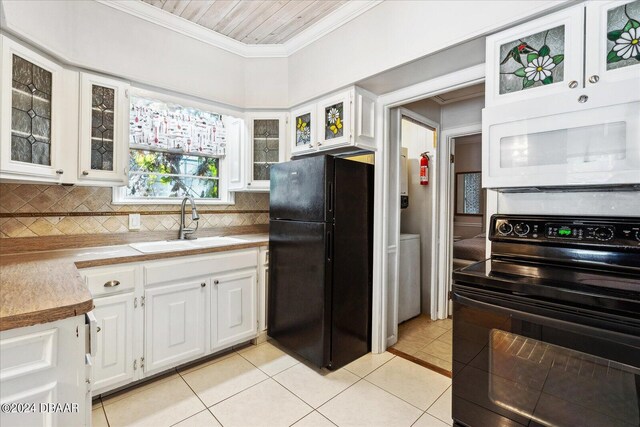 kitchen with black appliances, tasteful backsplash, white cabinetry, light tile patterned floors, and sink