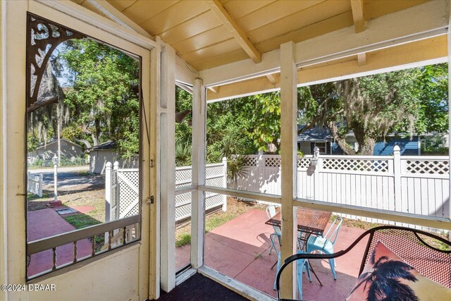 sunroom / solarium featuring plenty of natural light and vaulted ceiling with beams