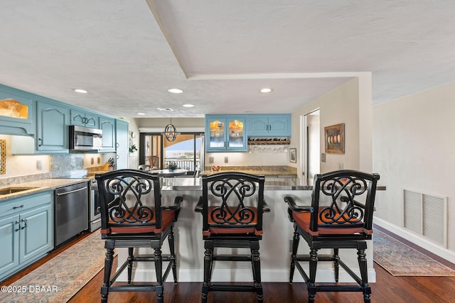 761 Marina Point Dr Unit 7610, Daytona Beach, FL 32114 - kitchen with blue cabinetry, visible vents, dark wood finished floors, stainless steel appliances, and decorative backsplash