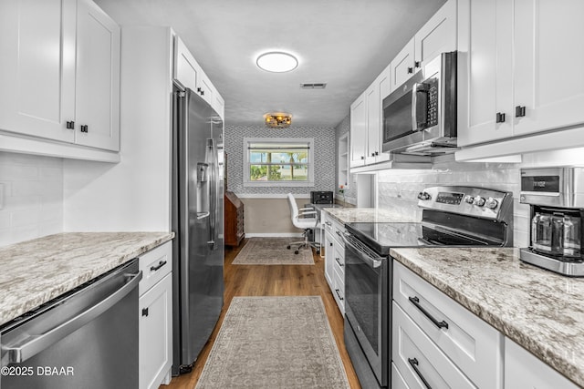 23 Briggs Dr, Ormond Beach, FL 32176 - kitchen with stainless steel appliances, dark wood-style flooring, and white cabinetry