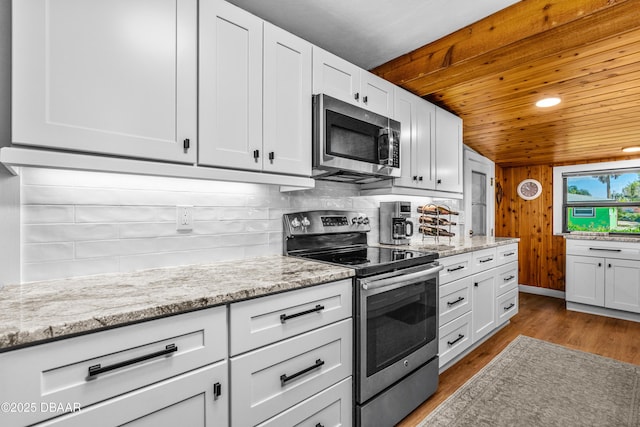 23 Briggs Dr, Ormond Beach, FL 32176 - kitchen featuring appliances with stainless steel finishes, wood ceiling, wood finished floors, white cabinets, and light stone counters
