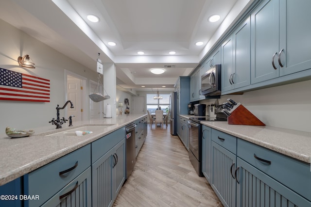 kitchen featuring blue cabinetry, appliances with stainless steel finishes, a raised ceiling, sink, and light hardwood / wood-style flooring