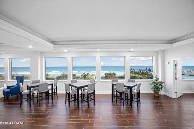 dining room featuring dark wood-type flooring, a water view, and crown molding