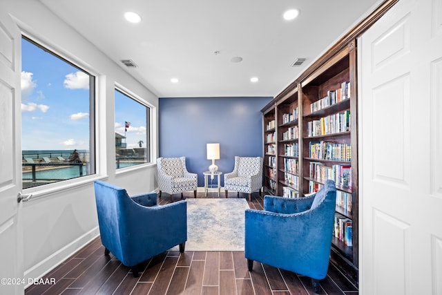 sitting room featuring dark wood-type flooring and a water view