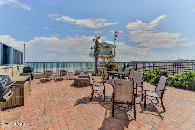 view of patio / terrace with grilling area, a water view, and an outdoor fire pit