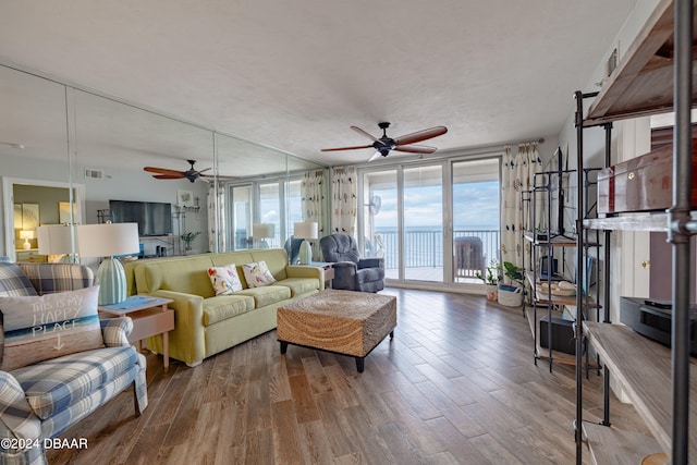 living room featuring hardwood / wood-style floors, ceiling fan, and a textured ceiling