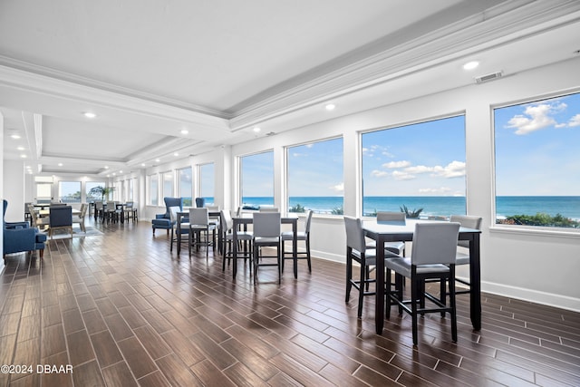 dining space featuring ornamental molding, dark hardwood / wood-style flooring, a water view, and a tray ceiling