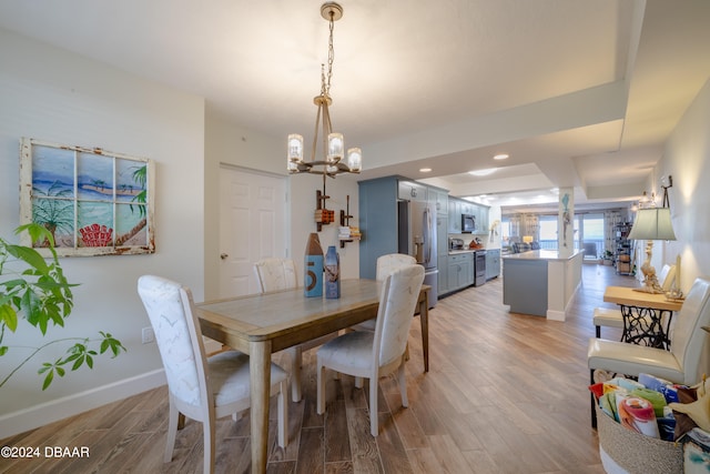 dining room with light hardwood / wood-style floors and a notable chandelier