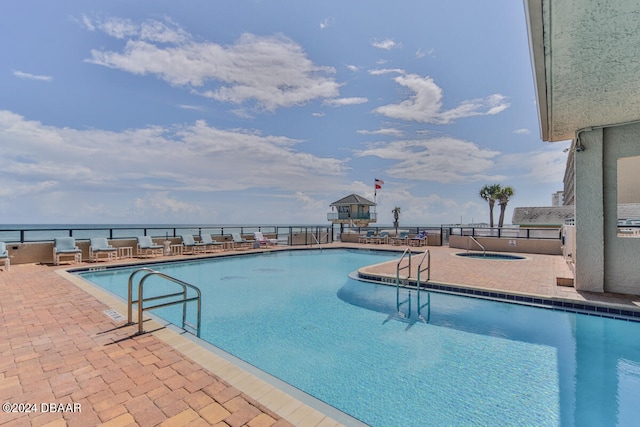 view of swimming pool with a patio area and a water view