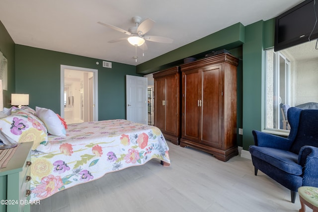 bedroom featuring ensuite bathroom, light hardwood / wood-style flooring, and ceiling fan