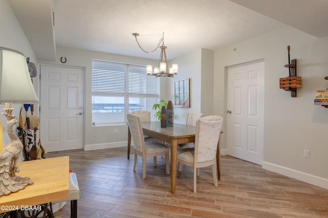 dining area with light hardwood / wood-style floors and a notable chandelier