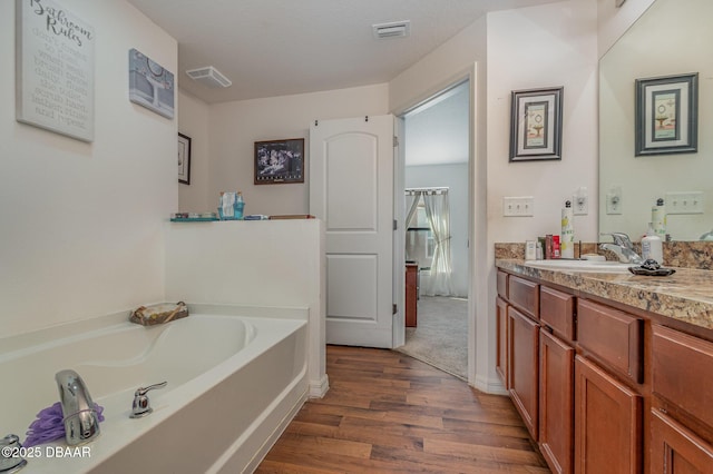 bathroom with hardwood / wood-style flooring, a bathtub, and vanity