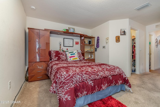 bedroom featuring a textured ceiling, light colored carpet, and a spacious closet