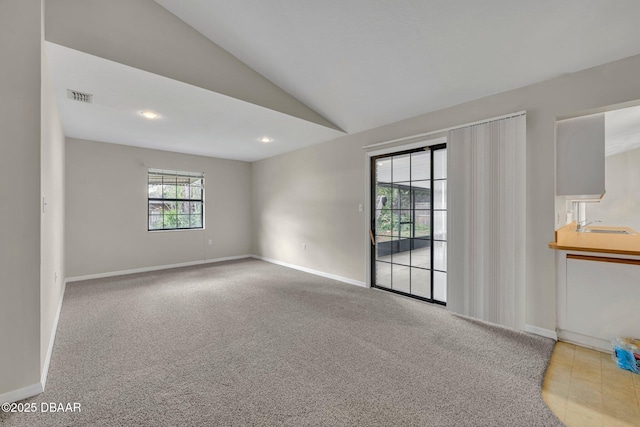 unfurnished room with visible vents, carpet flooring, baseboards, and vaulted ceiling