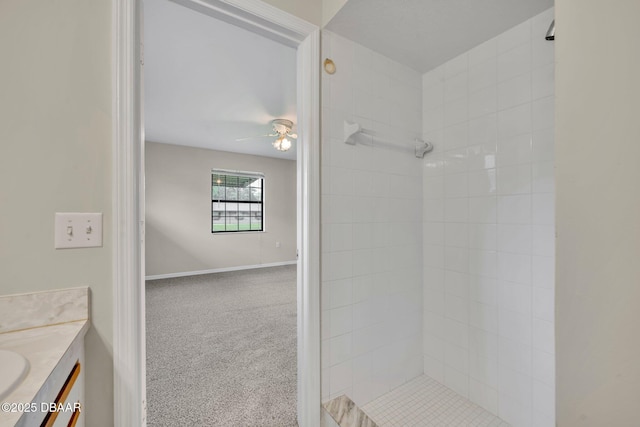 full bath with a tile shower, baseboards, vanity, and a ceiling fan