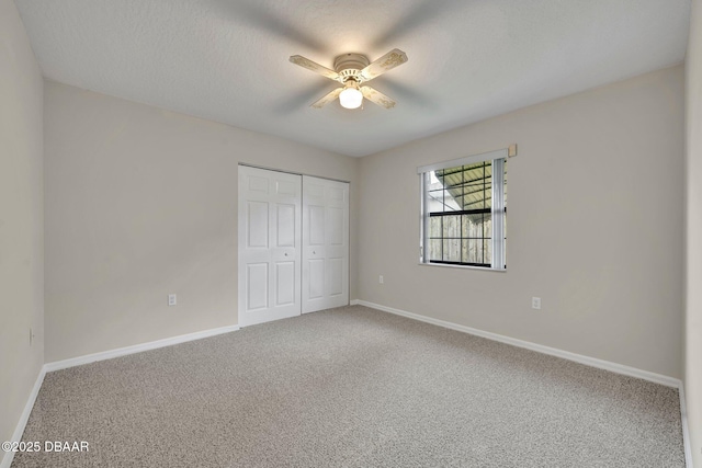 unfurnished bedroom featuring a ceiling fan, a textured ceiling, a closet, carpet floors, and baseboards