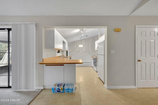 kitchen featuring a sink, baseboards, white appliances, and vaulted ceiling