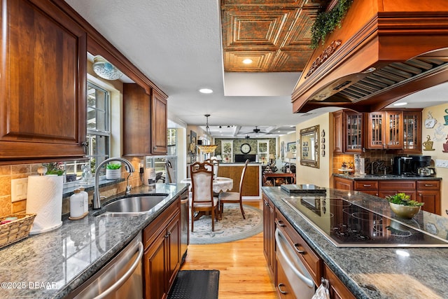 kitchen featuring black electric stovetop, custom exhaust hood, ceiling fan, sink, and light hardwood / wood-style flooring