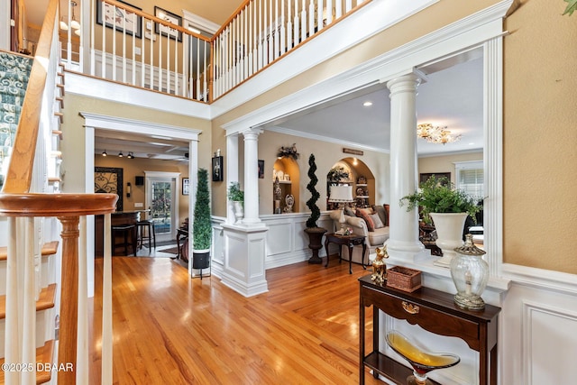 foyer entrance with decorative columns, light hardwood / wood-style flooring, and crown molding