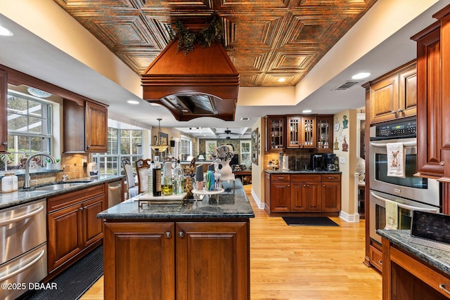 kitchen with sink, a kitchen island, light hardwood / wood-style floors, and appliances with stainless steel finishes